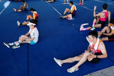 Nha Trang, Khanh Hoa Eyaleti, Vietnam - 11 Ağustos 2024: Birkaç VnExpress Nha Trang Maratonu katılımcısı saman minderinin üzerinde oturuyorlar ve yarıştan sonra dinleniyorlar