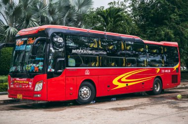 Arkalı koltuklu kırmızı bir Asya uyku otobüsü otoparkta bekliyor ve uçağa binmek için bekliyor. Nha Trang, Vietnam - 16 Aralık 2024