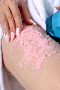 Deriyi temizlemek için fırçala. Ayak ovalama. Kadın kozmetolojisi. Mavi arka plan. Beyaz bornozlu bir kadın tatilde. Beyaz manikür. Güzel, bakımlı eller. Yüksek kalite