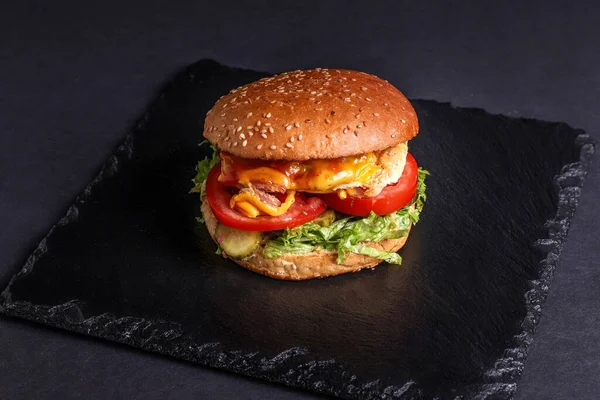 burger on a black background. Cut and fill. Meat and salad. Fast food minimalism. Junk food. Cholesterol. Peat board. Food stand Top view. Flatley.
