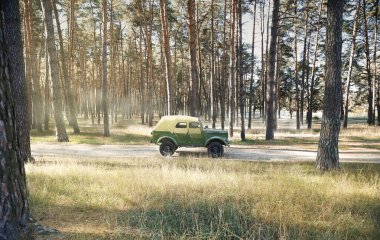 Askeri araç doğada. Hava güzel. Araba haki renginde. Kötü bir yolda büyük tekerlekleri olan bir araba. Yüksek kalite
