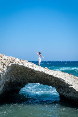 Tığ işi elbiseli kadın denizde doğal bir taş kemer üzerinde