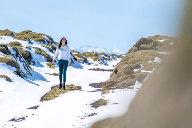 Güneşli bir günde İzlanda 'da karlı bir yolda yürüyen bir kadın.