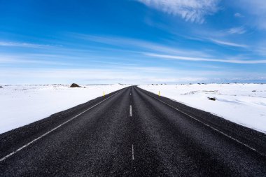 İzlanda 'da omzunda karla yapayalnız siyah asfalt yol