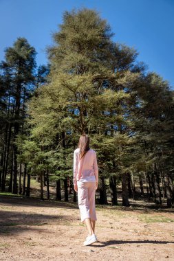 Soluk Pembe Elbiseli Genç Kadın Fas, Ifrane Cedar Ormanı 'nda duruyor.