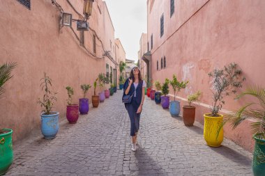 Marakeş 'in Kızıl Sokaklarında Yürüyen Genç Koyu Saçlı Kadın Etrafı Renkli Tencerelerle çevrili, Fas