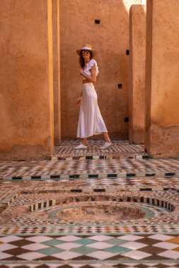 Beyaz elbiseli ve şapkalı genç siyah saçlı kadın El Badii Sarayı Marakeş Renkli fayanslı, Marakeş