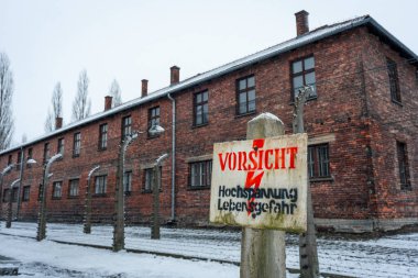 Uyarı işareti: Polonya 'nın karlı bir günde Auschwitz çitlerinde yüksek voltaj ölüm tehlikesi