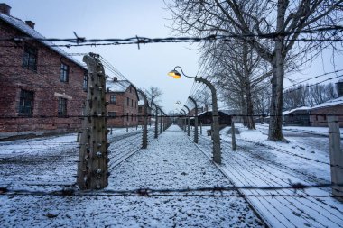 Polonya 'da, Auschwitz çitlerinde parlak sokak lambalarıyla karlı bir akşam.
