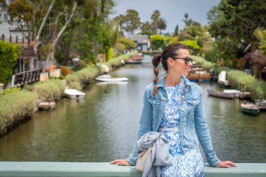 Bir kadın, Los Angeles, Kaliforniya 'da Venedik Mahallesi' nde güzel bir şekilde tekneler ve yemyeşil alanlarla çevrili büyüleyici bir kanalda huzurlu bir anın tadını çıkarıyor.