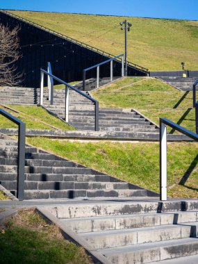 İnsanları Polonya 'nın Katowice kentindeki manzarasını keşfetmeye davet eden verimli, yeşil çimenli bir tepeye doğru zarif bir şekilde inşa edilmiş bir merdiven.