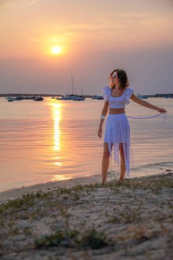 Genç bir kadın, deniz kenarında gün batımının güzelliğinden zevk alır. Huzurlu ve resimli bir sahne yaratır. Formentera, Balearic Adaları, İspanya 'da barışçıl yaşam tarzı ve doğa temalı projeler için ideal.