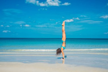 Yoga yapan ve sabah deniz kenarında elleri üzerinde duran bir kadın. Yüksek kalite fotoğraf