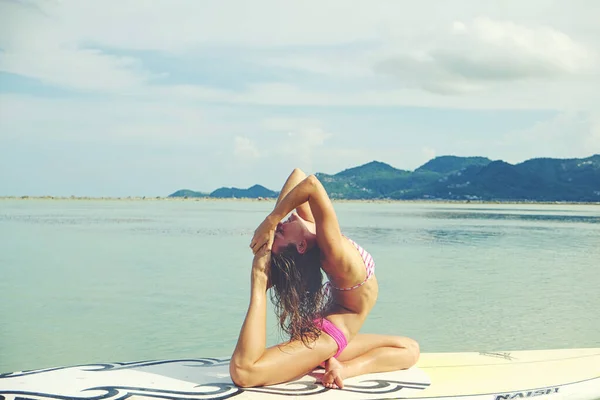 美丽的女运动员在日出时练习Sup瑜伽 高质量的照片 免版税图库图片