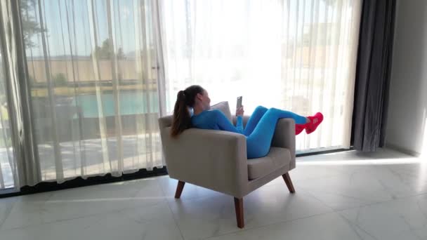 Видео Показывает Женщину Удобно Сидящую Кресле Рядом Большим Окном Роскошной — стоковое видео
