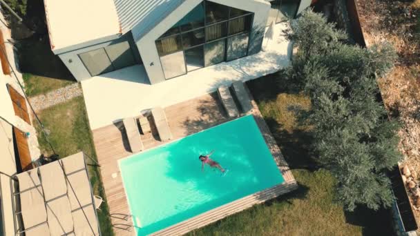 このビデオでは 豪華なプールヴィラの空中ショットが表示されます カメラが高く 緑に囲まれた別荘の美しい建築を見ることができます プールは焦点です — ストック動画