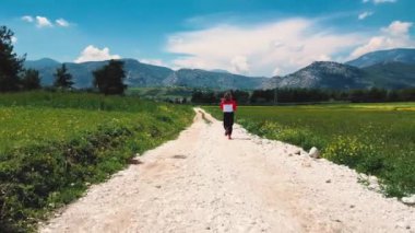 Arka planda dağlarla koşan atlet bir kadın, kırsal alanda antrenman yapıyor. Yüksek kalite 4k görüntü