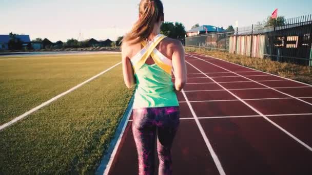 スタジアムでジョギングをする若い女性 ワイヤレスイヤホン アクティブライフスタイル スタジアムコースでのスポーティな女性トレーニング スポーツコンセプト Uhdについて 高品質の4K映像 — ストック動画