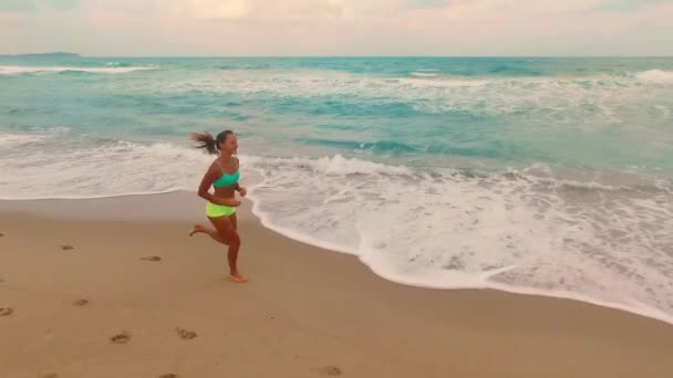 黄昏时 一个年轻姑娘在海滩上慢跑 蓝色的海浪冲刷着海滩 高质量的4K镜头 — 图库视频影像