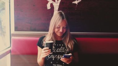 Akıllı telefon kullanan, kafede kahve içen sosyal medyada mesajlaşan, mobil teknolojiden hoşlanan genç bir kadın. Yüksek kalite 4k görüntü