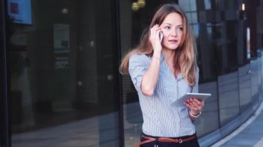Ofis dışında tablet ve akıllı telefon kullanan genç bir iş kadını. Yüksek kalite 4k görüntü