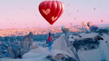 Kalp şeklinde sıcak hava balonu. Kadın yolcu, Türkiye 'nin Kapadokya kentindeki sıcak hava balonlarına bakıyor. 14 Şubat konsept videosu. Yüksek kalite 4k görüntü
