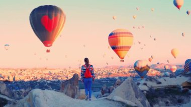 Kalp şeklinde sıcak hava balonu. Kadın yolcu, Türkiye 'nin Kapadokya kentindeki sıcak hava balonlarına bakıyor. 14 Şubat konsept videosu. Yüksek kalite 4k görüntü