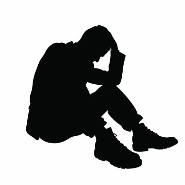 Kafası ellerinin arasında yerde oturan bir adam.