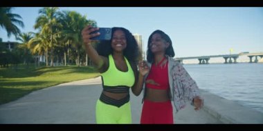 Parkta selfie çekerken gülümseyen ve eğlenen iki Afrikalı Amerikalı genç kadının ağır çekimleri.