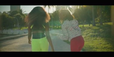 Parkta yürüyen ve eğlenen iki Afro-Amerikan genç kadının ağır çekimleri. Arkadan vurulmuş.. 