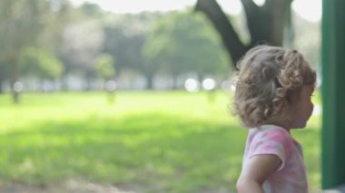 Cute little girl with pigtails playing on a slide at playground