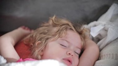 Beautiful little girl sleeping on top of blankets