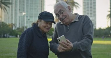 Güney Florida 'da bir parkta cep telefonlarına bakan yaşlı çiftin yavaş çekim görüntüleri.