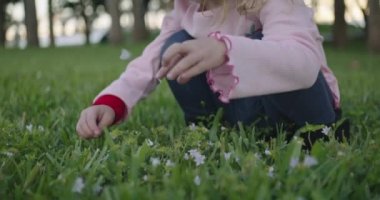 Slow motion medium shot of little girl playing at a park with buildings and trees in the background