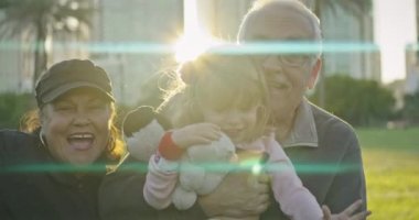 Beautiful medium shot of an attractive older couple looking at camera and smiling at a park in Florida while holding their beautiful granddaughter