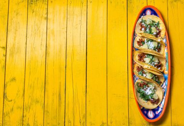 Tacos al pastor ve Meksika soslu Meksika yemeği. Sarı tahta arkaplan, kopyalama alanı, üst görünüm.