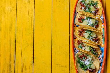 Tacos al pastor ve Meksika soslu Meksika yemeği. Sarı tahta arkaplan, kopyalama alanı, üst görünüm.