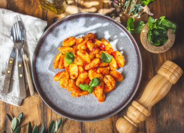 Domates soslu İtalyan Gnocchi ve ahşap arka planda fesleğen..