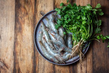 Çiğ deniz ürünleri. Kişniş gri tabaklı taze karidesler. Ahşap arka plan