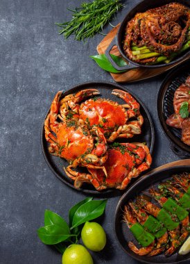 Bir dizi deniz ürünleri tabağı. Siyah arka planda yengeç, ahtapot, mürekkep balığı ve kaplan karidesleri var. Üst Manzara. Metin için alanı kopyala