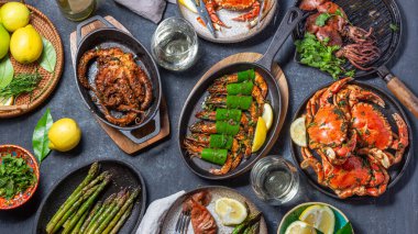 İçinde deniz ürünleri tabakları olan bir masa hazırla. Pişmiş yengeç, kaplan karidesi, ızgara ahtapot ve dökme demir tava ve tabakta mürekkep balığı, beyaz şarap. Üst görünüm.