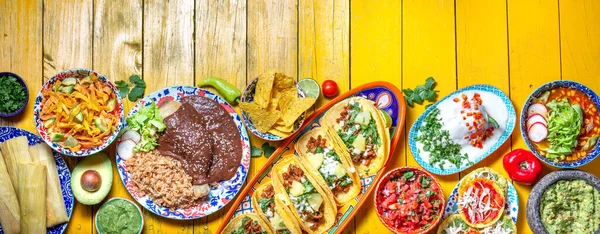 Mexican festive food for independence day - independencia chiles en nogada, tacos al pastor, chalupas pozole, tamales, chicken with mole poblano sauce. Yellow background