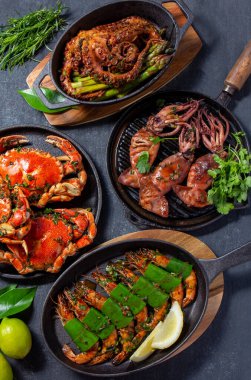 Bir dizi deniz ürünleri tabağı. Siyah arka planda yengeç, ahtapot, mürekkep balığı ve kaplan karidesleri var. Üst görünüm