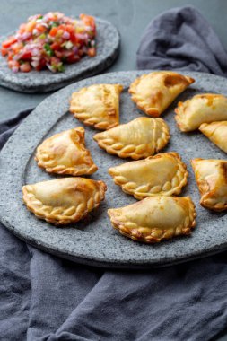 Domates sosu ve guacamole ile taş plaka üzerinde farklı küçük kokteyl Empanadas . Gri arka plan. Latin Amerika ve İspanyol tipical gıda. 