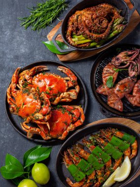 Bir dizi deniz ürünleri tabağı. Siyah arka planda yengeç, ahtapot, mürekkep balığı ve kaplan karidesleri var. Üst görünüm