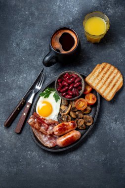 Kızarmış yumurta, sosis, domuz pastırması, siyah puding, fasulye, tost ve kahve ile İngiliz kahvaltısı..