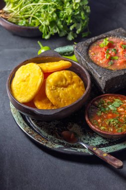 Sopaipilla. Latin Amerika yemekleri. Tipik salsa soslu geleneksel Şili ev yapımı balkabağı sopaipillası. Taş havan ve baharatlı peber soslu Chancho en piedra domates sosu..