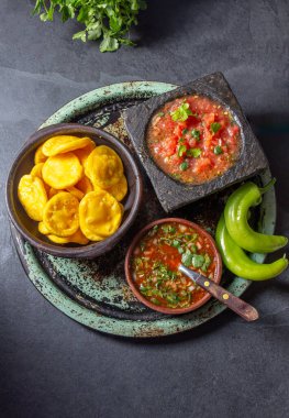 Sopaipilla. Latin Amerika yemekleri. Tipik salsa soslu geleneksel Şili ev yapımı balkabağı sopaipillası. Taş havan ve baharatlı peber soslu Chancho en piedra domates sosu..