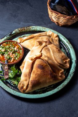 Tipik pişmiş empanadas de Pino, klasik denemede peber soslu, siyah taş arka planlı. Bağımsızlık Günü partisi için geleneksel Şili yemekleri.