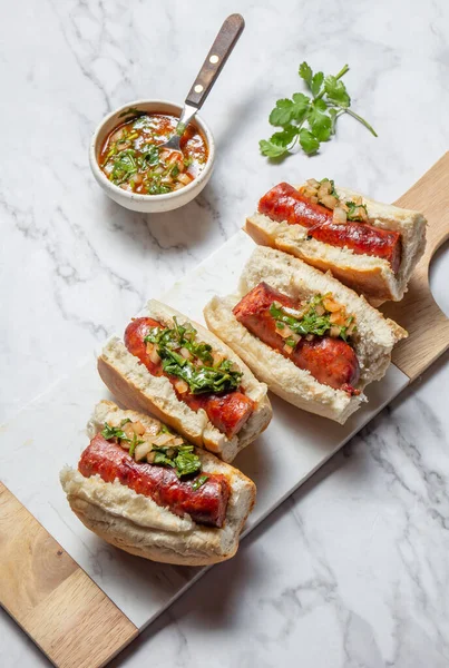 stock image Chilean and Argentinian food. Traditional choripan with spicy pebre, chorizo sandwich with chorizo sausages and bread